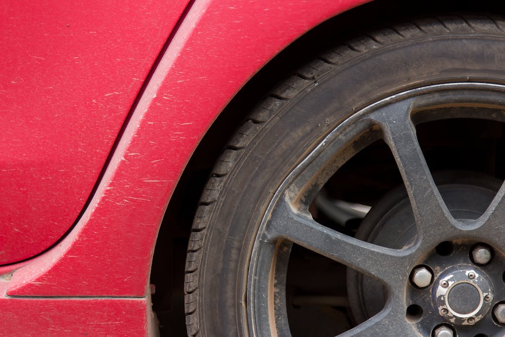 Detailed image of a red car's rusty wheel and tire showing texture and wear.
